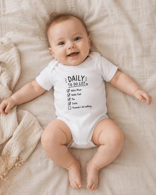 Daily To-Do List baby bodysuit lifestyle photo, white, baby smiling on bed