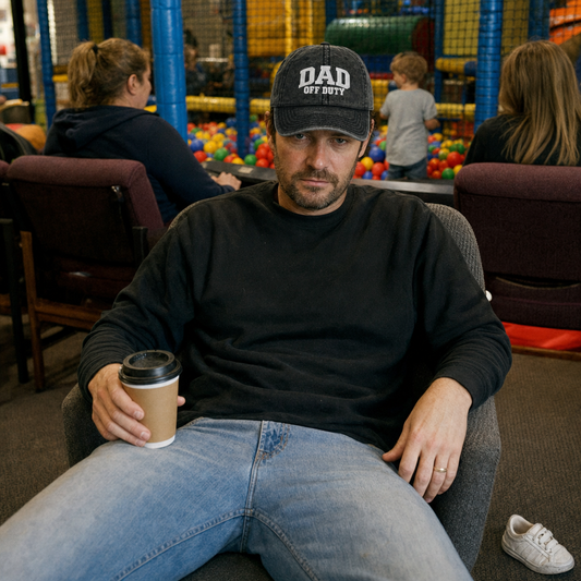 Washed black vintage cap embroidered “Dad Off Duty” in white, worn at a soft-play centre